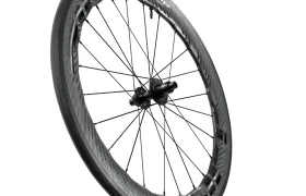 Se muestra una rueda de bicicleta de fibra de carbono Zipp 2026 con una llanta de sección profunda, radios planos y un buje central en ángulo sobre un fondo blanco, ideal para quienes buscan rodar más rápido.