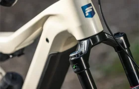 Primer plano del cuadro delantero, la horquilla y el manillar de una bicicleta de montaña eléctrica FOCUS e-MTB de color beige con un logotipo azul en el tubo de dirección, en el que se aprecian los elementos de diseño característicos de los últimos modelos JAM y SAM.
