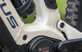 Primer plano del motor de una bicicleta eléctrica Bosch Performance CX, un puerto de carga y parte de un portabidón montado en un cuadro blanco de la e-MTB JAM 2027.