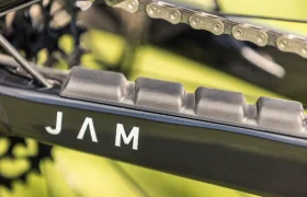 Primer plano de la vaina trasera de una bicicleta con la cadena, el protector de la vaina y la palabra «JAM» impresa en el cuadro negro: un detalle llamativo que destaca en la innovadora e-MTB JAM 2027.