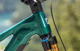 Primer plano del manillar y la horquilla de suspensión delantera de una bicicleta de montaña eléctrica Gama FOCUS e-MTB 2027 de color verde, fotografiada al aire libre con un fondo natural desenfocado.