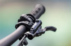 Primer plano del manillar de una bicicleta JAM e-MTB 2027, con especial atención a la palanca de freno y al puño, sobre un fondo desenfocado.