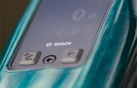 Primer plano de un panel de pantalla digital de Bosch en una bicicleta eléctrica de montaña (e-MTB) FOCUS de color verde, en el que se aprecian los botones y una imagen tenue en la pantalla.