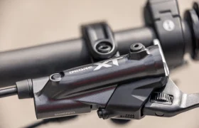 Primer plano de una palanca de freno y un manillar Shimano Deore XT en una bicicleta eléctrica de montaña (e-MTB) de la marca FOCUS, en el que se aprecian el texto de la marca y los detalles mecánicos.