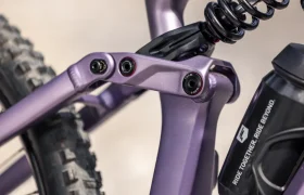 Primer plano del cuadro morado de una bicicleta eléctrica de montaña (e-MTB) FOCUS 2027, en el que se aprecian el sistema de suspensión trasera, el muelle helicoidal y parte de un bidón de agua montado en el cuadro.