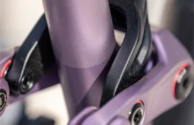 Primer plano de un cuadro de suspensión morado de la bicicleta eléctrica de montaña (e-MTB) SAM 2027, en el que se aprecian los pernos del pivote, el muelle del amortiguador y el sistema de articulación del cuadro.