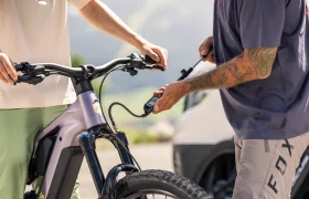 Dos personas conectan una bomba de aire a la rueda delantera de una bicicleta eléctrica de montaña Gama FOCUS 2027 al aire libre.
