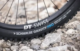 Primer plano de una rueda de bicicleta de montaña sobre terreno rocoso, en el que se aprecia una llanta DT Swiss y un neumático Schwalbe Gravity Pro Magic Mary de 29 x 2,5 pulgadas con la banda de rodadura visible, ideal para afrontar senderos exigentes con los modelos Gama FOCUS e-MTB 2027 JAM o SAM.
