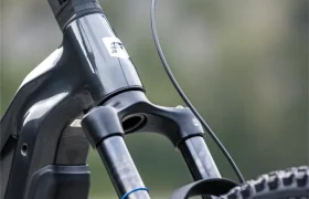 Primer plano de la parte delantera de una moderna bicicleta eléctrica de montaña FOCUS e-MTB 2027, en el que se aprecian el manillar, la horquilla de suspensión delantera y la rueda delantera, con la marca Maxxis bien visible.