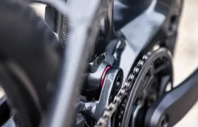 Primer plano de la cadena, el juego de bielas y parte del cuadro de una bicicleta eléctrica de montaña (e-MTB) FOCUS, en el que se aprecian los componentes metálicos y un detalle en rojo cerca del plato.