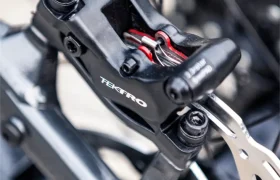 Primer plano de una pinza de freno de disco hidráulico Tektro montada en una bicicleta FOCUS e-MTB 2027, en el que se aprecian el disco de freno y la funda.