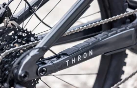 Primer plano del mecanismo de cambio trasero y la vaina de una bicicleta, con la palabra «THRON» impresa en el cuadro, un detalle de diseño que también se aprecia en los últimos modelos de e-MTB 2027.