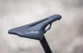 Primer plano de un sillín de bicicleta Selle Italia negro montado en una tija de sillín, con un fondo neutro difuminado como telón de fondo: perfecto para la aventurera e-MTB 2027 THRON JAM.
