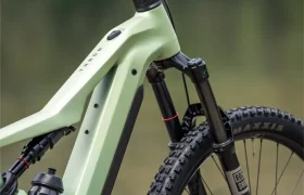 Primer plano de una bicicleta de montaña eléctrica FOCUS e-MTB 2027 de color verde, en el que se aprecian el manillar, la horquilla de suspensión delantera y parte del cuadro con un bidón de agua acoplado.