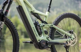 Primer plano de una bicicleta eléctrica de montaña Focus THRON de color verde, en el que se aprecian el cuadro, el motor Bosch, el bidón, la suspensión trasera y parte de la rueda trasera.