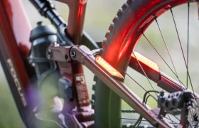 Primer plano de la rueda trasera y el cuadro de una bicicleta eléctrica de montaña JAM e-MTB 2027, en el que se aprecian dos luces LED de color rojo brillante instaladas para mejorar la visibilidad y la seguridad.