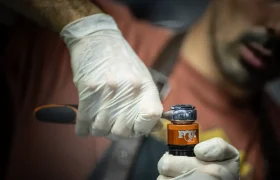 Una persona que lleva guantes utiliza una herramienta para ajustar un amortiguador FOX de color naranja.