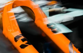 Primer plano de una horquilla de suspensión naranja para bicicleta de montaña con motivos gráficos negros, fotografiada en un interior con el fondo desenfocado.