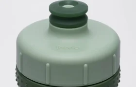 Primer plano de un tapón antimicrobiano «Fabric Gripper V2» de color verde y gris claro, con superficie texturizada para un mejor agarre y una boquilla circular de tipo «push-pull» en la parte superior, que ofrece protección permanente para la hidratación diaria.