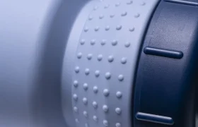 Primer plano de una botella de agua o termo azul claro con textura y tapón azul oscuro, en el que se aprecian la zona de agarre y parte de la tapa. Con el diseño «Fabric Gripper V2», este bidón antimicrobiano ofrece protección permanente para el uso diario.