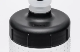 Primer plano de un bidón translúcido con tapón negro y boquilla transparente de tipo «push-pull», que presenta puntos texturados en relieve en la superficie de la botella para mejorar el agarre, ideal para usar con el Fabric Gripper V2.