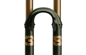 Vista frontal de una horquilla de suspensión FOX 38 Racing Green Edición Limitada para bicicletas de montaña, con una llamativa combinación de colores verde y dorado con la marca y los mandos de ajuste visibles.