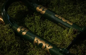 Primer plano de una horquilla de suspensión de bicicleta de montaña FOX 38 Racing Green Edición Limitada de color verde oscuro apoyada sobre musgo verde.