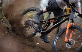 Un ciclista de montaña derrapa y pierde el control en un camino de tierra, levantando tierra y escombros cuando los amortiguadores FOX de la moto se inclinan bruscamente hacia un lado.