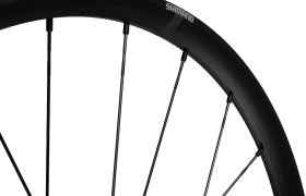 Primer plano de una llanta de bicicleta Shimano negra con radios, sobre fondo blanco.