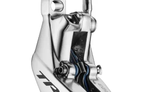 Primer plano de una pinza de freno de disco hidráulica TRP EVO PRO plateada para bicicletas, edición limitada, en la que se aprecian los orificios de montaje y la fijación del latiguillo de freno.