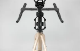 Vista desde arriba de la sección delantera de una bicicleta, mostrando el manillar, la potencia y un portaaccesorios de la marca Topeak montado en el tubo de dirección junto a un Tailfin Hydromount.