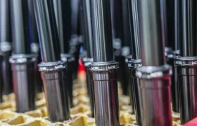 Primer plano de varias tijas metálicas de bicicleta, incluida una tija telescópica inalámbrica RAGE Circuit, colocadas verticalmente en un soporte de cartón tipo panal.