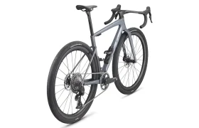 Una moderna BMC Kaius 01 gris para gravel con manillar rebajado, frenos de disco y neumáticos anchos, vista desde la parte trasera derecha sobre fondo blanco: una bicicleta rápida para cualquier terreno.