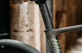Primer plano del sillín, la tija del sillín y la rueda trasera de una bicicleta moderna Ridley Kanzo Fast 2.0, equipada con neumáticos aerodinámicos de 58 mm, con un muro de piedra como fondo.