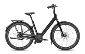 Una bicicleta urbana Moustache Lundi 27 de color negro, con cuadro abierto, portaequipajes trasero, guardabarros y frenos de disco, fotografiada de perfil sobre un fondo blanco: perfecta para desplazarse con estilo por la ciudad.