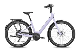 Una bicicleta urbana de cuadro abierto de color morado claro, inspirada en el diseño de la Moustache Lundi 27, con portaequipajes trasero, sillín negro y manillar recto —perfecta para moverse por la ciudad—, vista de perfil sobre un fondo blanco.