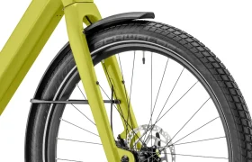 Primer plano de la rueda delantera de una bicicleta amarilla «Moustache Lundi 27», en el que se aprecian el neumático, los radios, el freno de disco, el guardabarros y parte del cuadro: perfecta para moverse por la ciudad con estilo.