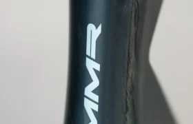 Primer plano del tubo de dirección de una bicicleta con el logotipo "MMR" en blanco sobre un cuadro metálico oscuro, mostrando el elegante diseño de la MMR Aelion SL, una auténtica bici asturiana.