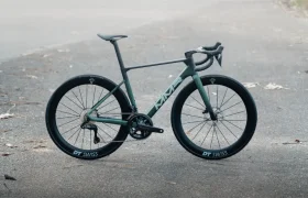 Una moderna bicicleta de carretera MMR Aelion con manillar drop y ruedas DT Swiss está aparcada en una superficie pavimentada al aire libre.