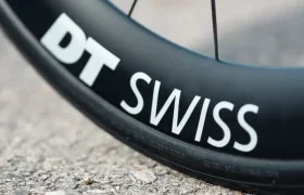 Primer plano de una llanta de bicicleta con la marca "DT SWISS", colocada sobre una superficie de pavimento con textura, perfecta para mejorar su MMR Aelion o cualquier actualización total de bicicleta.