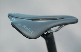 Primer plano de un sillín de bicicleta Selle Italia negro con un diseño elegante y ergonómico, montado en una tija MMR Aelion SL sobre un fondo neutro. Ideal para entusiastas de la bici total.