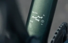 Primer plano de un cuadro de bicicleta total con la etiqueta "AELION SL SIZE M" y parte del plato visible.
