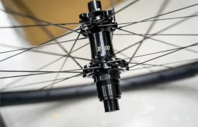 Primer plano de un buje de bicicleta negro con la inscripción «X-300» y radios que se extienden radialmente, montado en una rueda KFX i30 de la reconocida gama Ruedas FSA, sobre un fondo desenfocado, que pone de manifiesto la precisión y el control totales en cada detalle.