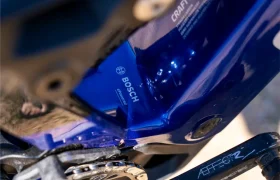 Primer plano de un sistema eBike de Bosch con el kit de mejora de rendimiento «Bosch Performance Upgrade» instalado en un cuadro de bicicleta azul, en el que se aprecia parte del brazo de la biela y el plato, lo que proporciona un mayor control y potencia.