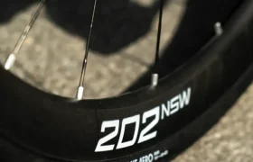 Primer plano de una rueda de bicicleta Aero Front en la que se aprecian las etiquetas «202 NSW» y «Schwalbe Pro One Aero» en la llanta, con el pavimento como fondo.