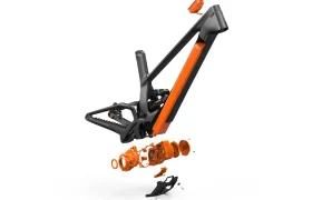 Vista ampliada del cuadro de bicicleta naranja y negro UNNO MITH, que muestra componentes y piezas separados sobre un fondo blanco.