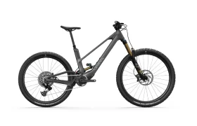 La UNNO MITH es una bicicleta de montaña eléctrica gris mate que presenta neumáticos gruesos, una horquilla de suspensión, un amortiguador trasero y frenos de disco, todo sobre un fondo blanco impecable.