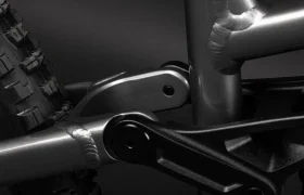 Primer plano de la suspensión trasera y el neumático de una bicicleta Santa Cruz Vala AL, destacando las piezas del cuadro de aluminio, las soldaduras y las juntas mecánicas sobre un fondo oscuro.