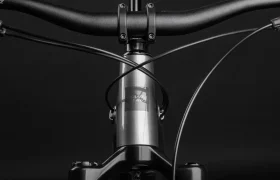 Primer plano del manillar de aluminio, los cables y el tubo de dirección de una bicicleta Santa Cruz Vala AL con el logotipo de Santa Cruz, sobre un fondo negro.