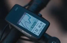 Un ciclocomputador montado en el manillar muestra la velocidad, la distancia, un mapa de navegación con detalles de la ruta y los desniveles, ideal para los ciclistas inspirados en la búsqueda de aventuras de Kilian Jornet.